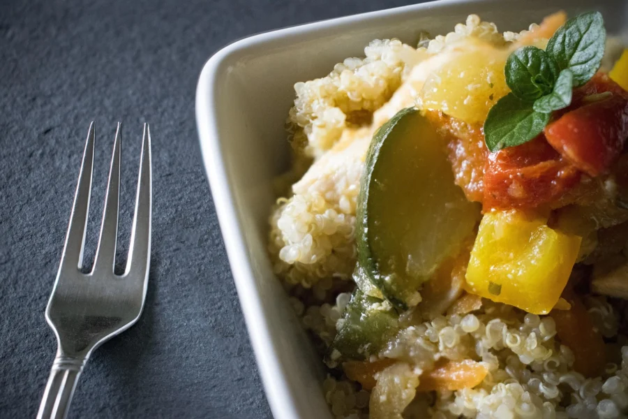 Fluffing cooked quinoa with a fork in a pot